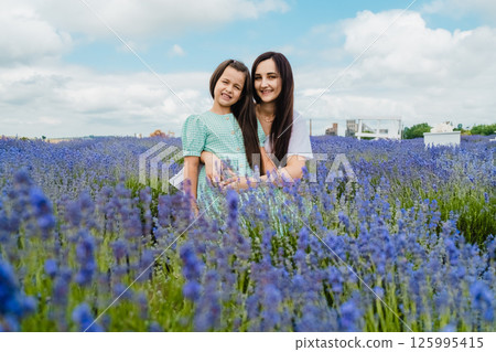 Mother and daughter smiling in a lavender field. A beautiful European girl with a woman in the lavender field. 125995415
