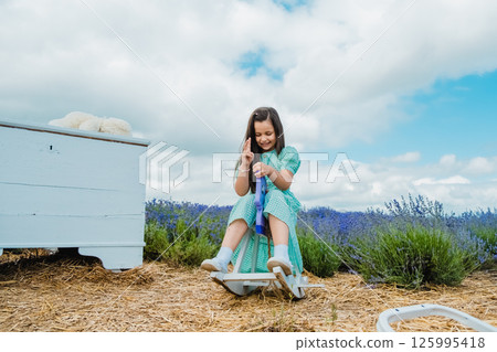 Girl sitting on a toy rocking horse made of wood in a lavender field.  125995418