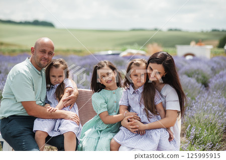 A family dressed in festive clothes is spending time in a lavender field. A family dressed in festive clothes is spending time in a lavender field. 125995915