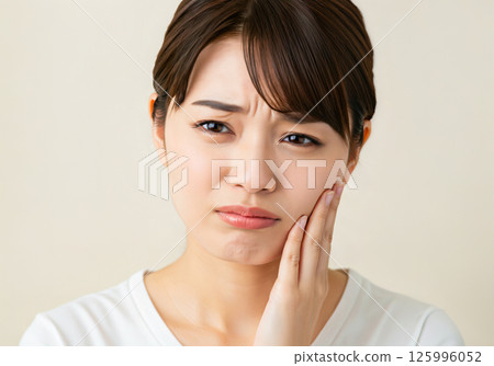 A woman holding her cheek because of a toothache A woman holding her cheek because of a toothache 125996052