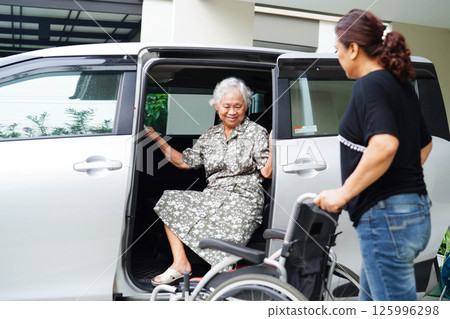 Caregiver help Asian elderly woman disability patient get in her car. 125996298