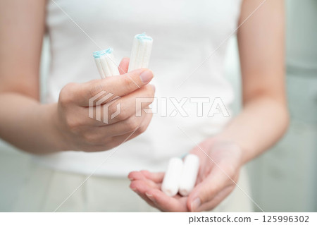 Asian woman holding cotton tampons for hygiene menstrual period cycle protection. Asian woman holding cotton tampons for hygiene menstrual period cycle protection. 125996302