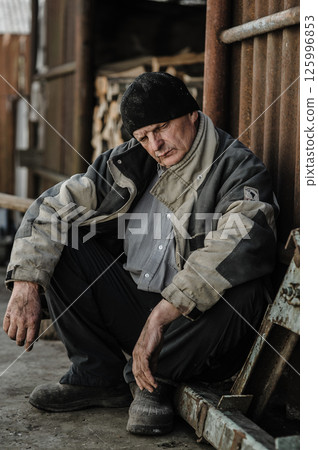 A pensioner sits quietly, his face full of sadness. A pensioner sits quietly, his face full of sadness. 125996853