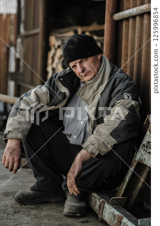 A pensioner sits quietly, his face full of sadness.  125996854