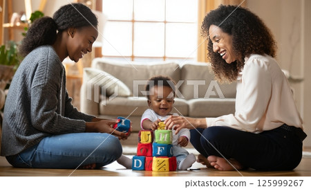 Two Moms Playing with Their Baby on the Floor of a Sunlit Living Room Two Moms Playing with Their Baby on the Floor of a Sunlit Living Room 125999267