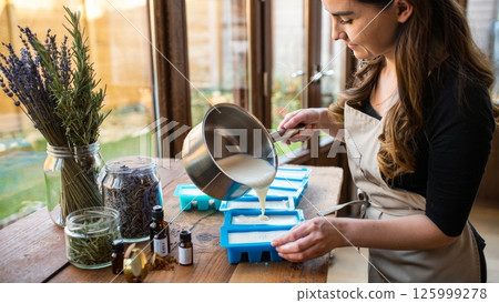 Woman Pouring Handmade Soap into Molds in Natural Light 125999278