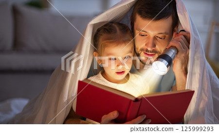 Parent Reading to Child Under Blanket Fort with Flashlight 125999293