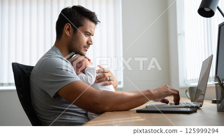 Single Dad Balancing Baby and Laptop in Home Office 125999294