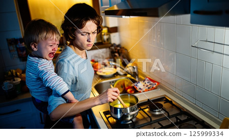 Parent Holding Screaming Toddler While Stirring Pot on Stove 125999334