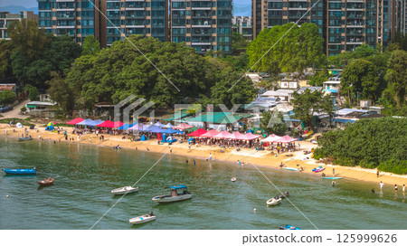 Busy Sandy Beach With Tents and Boats Below Urban Apartments May 4 2025 125999626