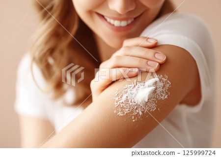 A woman applies coconut oil to her elbows enhancing moisture and skin health in her daily skincare routine. 125999724