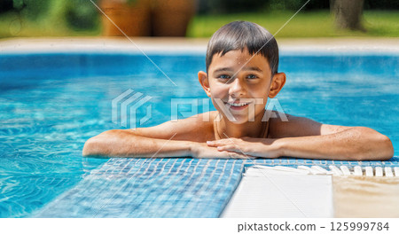 Happy boy swimming in swimming pool. Long-haired schoolboy in blue shorts smiling at camera Happy boy swimming in swimming pool. Long-haired schoolboy in blue shorts smiling at camera 125999784
