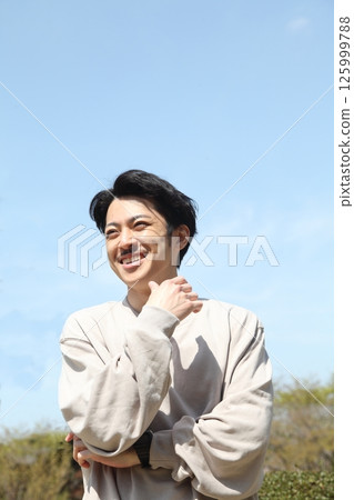 Smiling young man looking into the distance lifestyle image Smiling young man looking into the distance lifestyle image 125999788