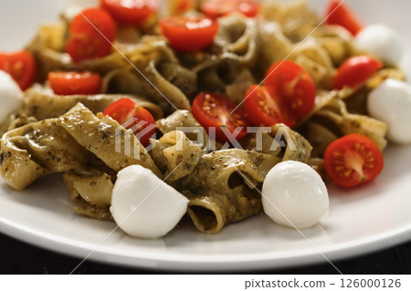 fettuccine with pesto, tomatoes and mozzarella on white plate fettuccine with pesto, tomatoes and mozzarella on white plate 126000126