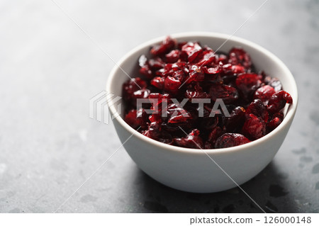 Dried cranberries in white bowl on concrete surface 126000148