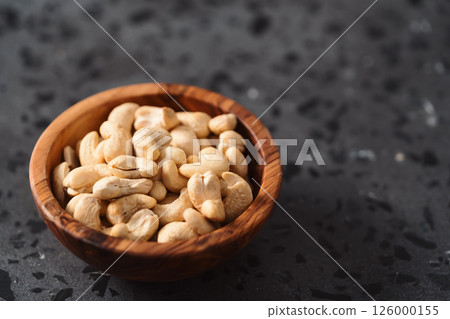 Dry cashew nuts in wood olive bowl on concrete background with copy space Dry cashew nuts in wood olive bowl on concrete background with copy space 126000155