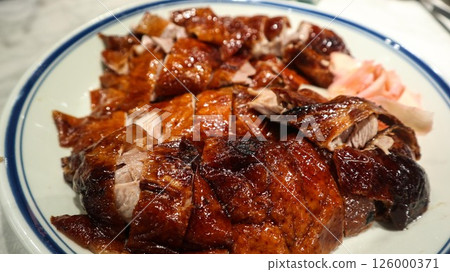 close up of Cantonese roasted goose cut into pieces with ginger slices on the side 126000371