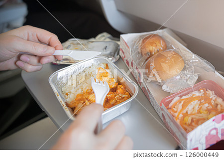 Enjoying InFlight Meal Experience Featuring Rice and Rolls Served on an Airplane Tray During the Flight. enjoying a delicious inflight meal with rice and fresh bread rolls, served on an airplane tray 126000449