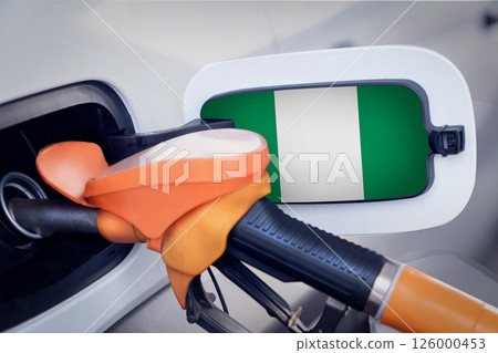 The Nigeria flag on the lid of the gas tank of a car at a gas station in close-up. High or low gasoline prices at Nigerian gas stations. In Nigeria, gasoline prices are rising due to a shortage of The Nigeria flag on the lid of the gas tank of a car at a gas station in close-up. High or low gasoline prices at Nigerian gas stations. In Nigeria, gasoline prices are rising due to a shortage of 126000453