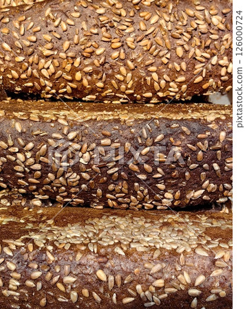 freshly baked loaves whole grain bread topped with sunflower seeds in bakery display. 126000724