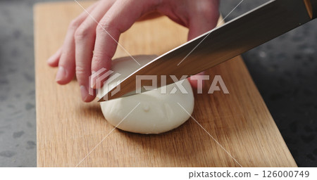 Closeup man slicing fresh mozzarella on oak board 126000749