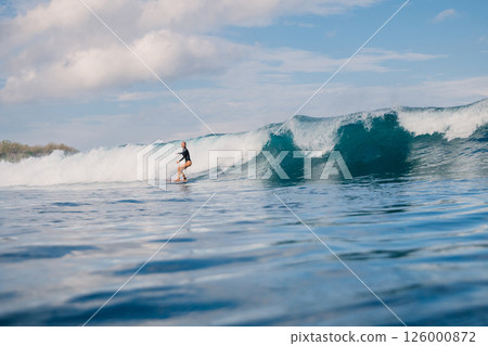 Female surfer riding on crashing blue wave and the beauty of surfing in ocean. 126000872