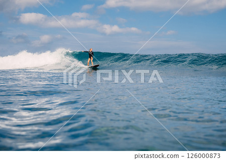 Surfgirl riding on crashing blue wave on a sunny day, beauty of surfing in ocean. Surfgirl riding on crashing blue wave on a sunny day, beauty of surfing in ocean. 126000873
