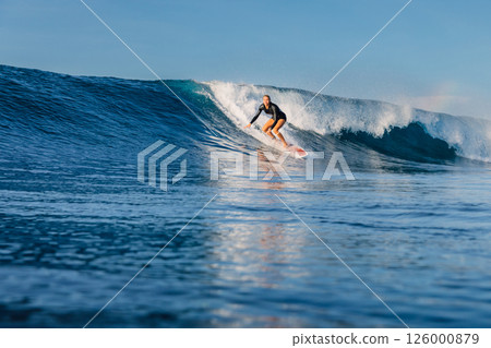 Surfer woman riding on breaking blue wave, surfing in Bali. 126000879
