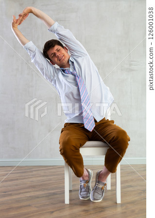 Young guy office worker doing exercises on chair Young guy office worker doing exercises on chair 126001038