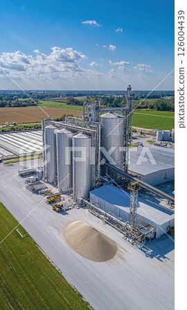 Modern agricultural storage facility with grain silos under blue sky in rural landscape 126004439