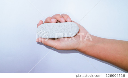 Asian girl holding a pumice stone on white background  126004516