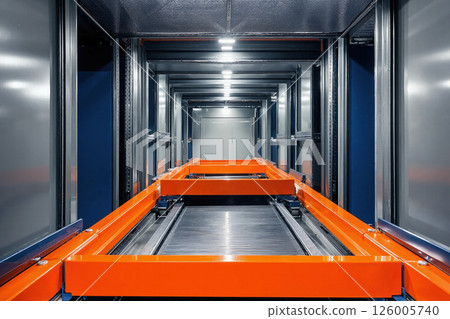Modern industrial conveyor system in a futuristic warehouse setting with bold orange and blue steel design 126005740