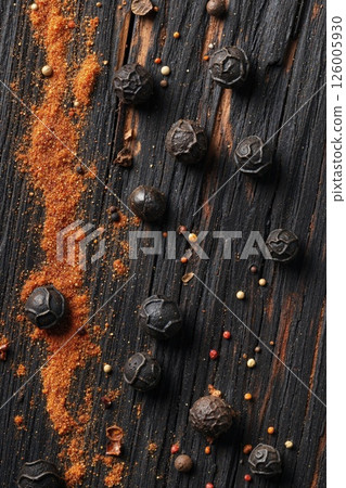 Rustic culinary aesthetics: black peppercorns and spices on charred wood for authentic cuisine and food art inspiration 126005930