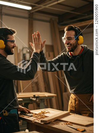 Craftsmen enthusiasm: collaborative woodworking in workshop setting with celebration 126005960