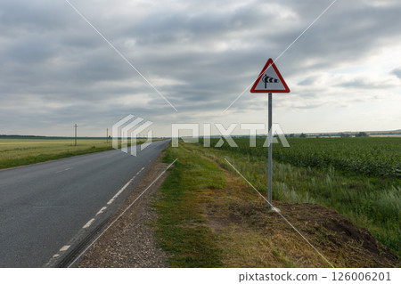 Crosswind warning sign along a rural road in the countryside during cloudy weather 126006201