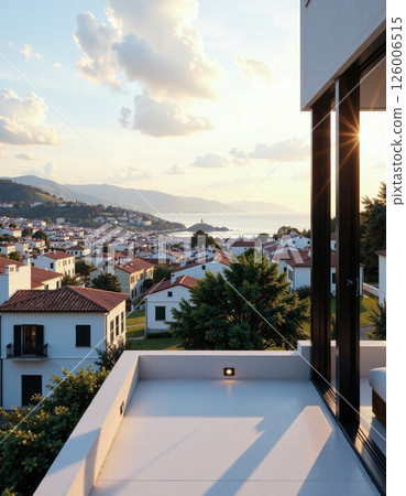 Serene coastal sunset view from modern terrace overlooking seaside village with red roofs and calm horizon 126006515