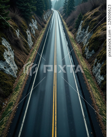 Majestic mountain road in serene winter landscape with lush green pines and rock formations 126006623
