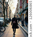 Urban stroll at sunset: woman walking down vibrant city street with shops and bicycles 126006865