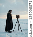 Vintage photography in winter landscape with tripod and fur coat ensemble 126006871
