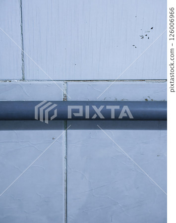 Water pipe on light blue tiled wall has slight stains 126006966
