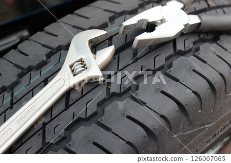 Pliers And Adjustable Wrench On A Spare Car Tire  126007065