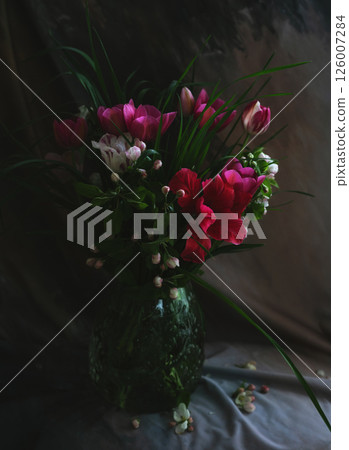 Dark still life with a bouquet of spring flowers in a glass vase 126007284