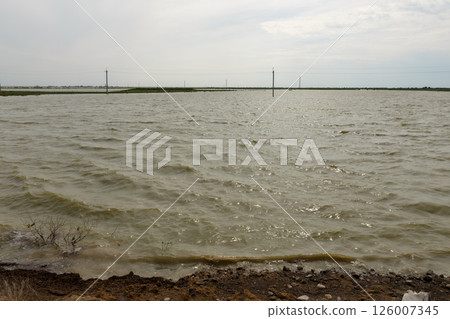 Flooded steppe landscape with power line poles submerged in water after flood in Kazakhstan 126007345