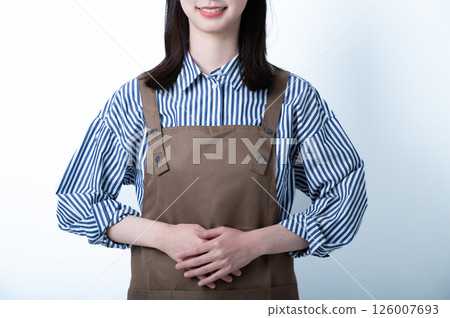 一位繫著圍裙的女士站著，雙手整齊地排列 126007693