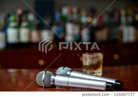 A microphone and a whiskey glass on a bar counter A microphone and a whiskey glass on a bar counter 126007727