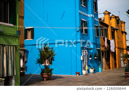 Colourful houses on the island of Burano, Italy, known for its brightly coloured facades and charming canals. Brightly coloured buildings line the narrow streets and waterways, horizontal photo 126008644