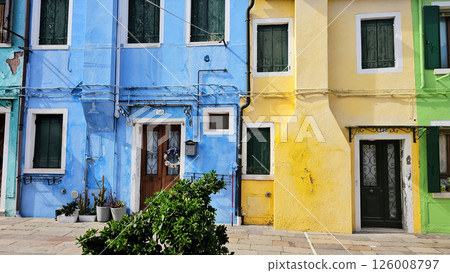 Colourful houses on the island of Burano, Italy, known for its brightly coloured facades and charming canals. Brightly coloured buildings line the narrow streets and waterways, horizontal photo 126008797
