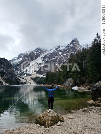 Mountain lake Braies in Italy. Girl in front of the lake looks at the beautiful landscape Mountain lake Braies in Italy. Girl in front of the lake looks at the beautiful landscape 126008815