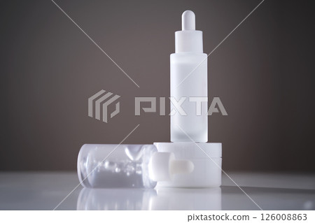 Two serums and a cream in a jar in the rays of the sun. Two serums and a cream in a jar in the rays of the sun. 126008863