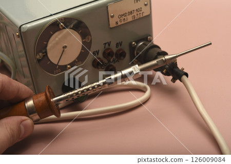 Retro soldering station. An old soldering iron with a silver tip. 126009084